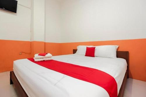 a bedroom with a large bed with red and white sheets at RedDoorz Near Jalan Jendral Sudirman in Manado