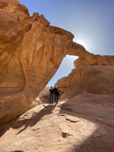 two people walking through an arch in the desert at Wadi Rum Khalid luxury camp in Wadi Rum