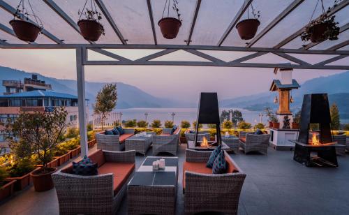 Un patio con sillas y mesas y vista al agua. en Himalayan Glory Inn, en Pokhara