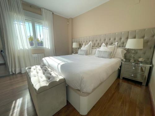 a bedroom with a large white bed with a large headboard at Chalet exclusivo bonalba in Alicante