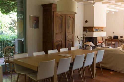 a dining room with a wooden table and white chairs at Les Pamplemousses charmante villa proche de la mer in Porquerolles