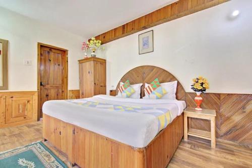 a bedroom with a large bed with a wooden headboard at Hotel Gangri By WB Inn in Manāli