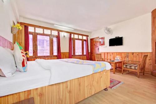 a bedroom with a large bed and a television at Hotel Gangri By WB Inn in Manāli