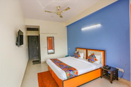 een slaapkamer met een blauwe muur en een bed bij FabHotel Red Roof Residency in Noida