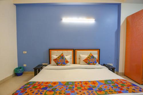 een slaapkamer met een groot bed met een blauwe muur bij FabHotel Red Roof Residency in Noida