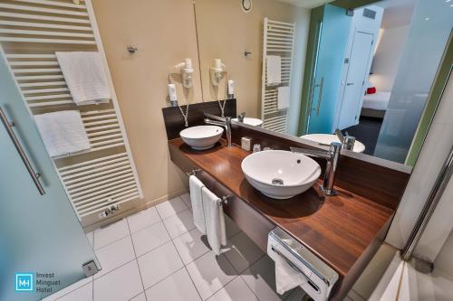 a bathroom with two sinks and a large mirror at Hotel De La Couronne Liege in Liège
