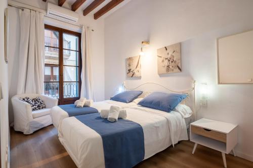 een slaapkamer met 2 bedden en een stoel. bij Holiday Palma Apartments - TI in Palma de Mallorca