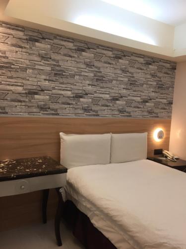 1 dormitorio con cama y pared de piedra en Ji Pin Hotel, en Xinzhuang