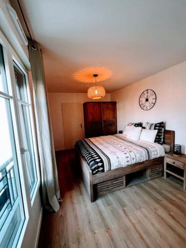 une chambre avec un lit et une horloge au mur dans l'établissement LOTUS- 4 min de Walt Disney-Arrivée autonome-Parking et Wifi gratuit-Proche de toutes commodités 5Min de la vallée village, à Chessy