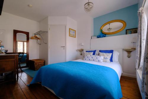 a blue and white bedroom with a bed and a mirror at Collier's BnB in Bruges