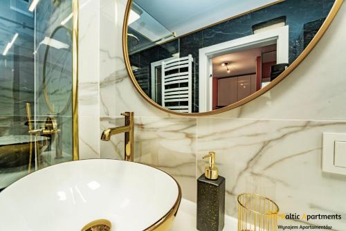 W łazience znajduje się biała umywalka i lustro. w obiekcie Baltic Apartments - Sun Towers w Świnoujściu
