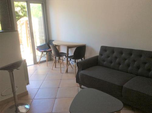 a living room with a couch and a table with chairs at Cap Agde Studio-Cabine jardin clos, port et plage in Cap d'Agde