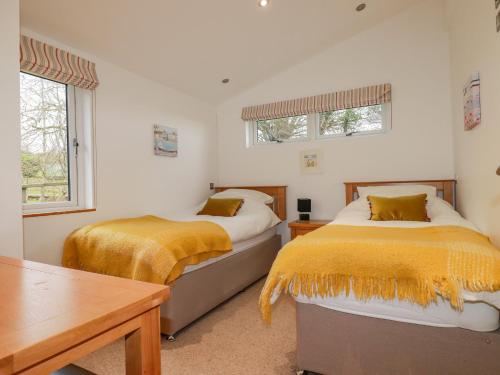 two beds in a room with white walls and windows at 10 Faraway Fields in Liskeard