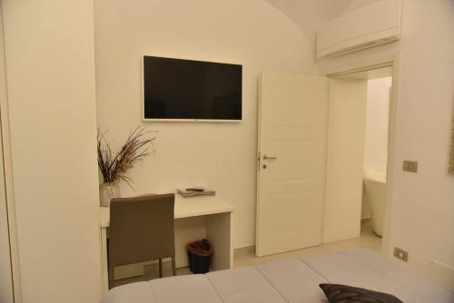 a white room with a desk and a television on the wall at Conte Max Rooms in Termoli
