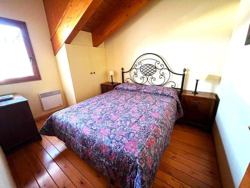 a bedroom with a bed with a floral bedspread and a window at Bonita casa adosada con gran jardín in Osséja