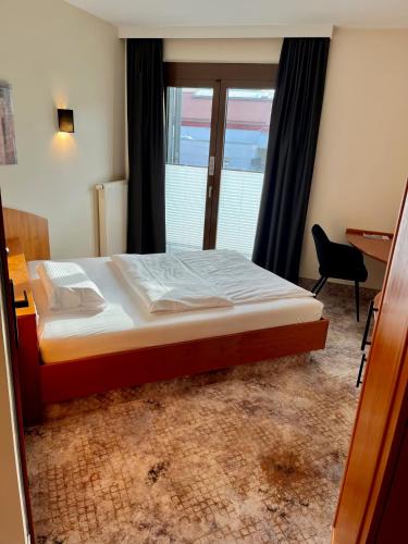 a bedroom with a bed and a desk and a window at Hotel Schiller in Olching