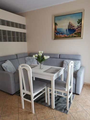 a living room with a table and chairs and a couch at Apartament Spacerowa z balkonem in Kołobrzeg
