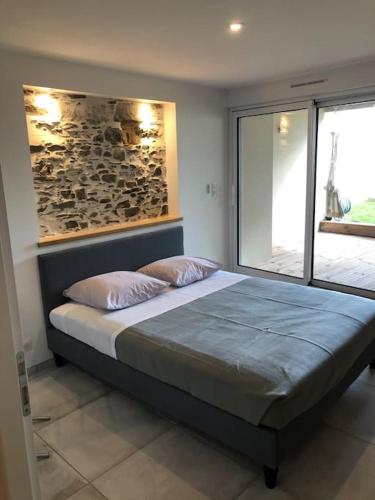 une chambre avec un lit avec un mur en pierre dans l'établissement Les Palmiers. Charme, spa et massage en vignoble nantais, au Pallet