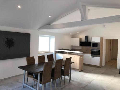 une cuisine avec une table et des chaises dans une pièce dans l'établissement Les Palmiers. Charme, spa et massage en vignoble nantais, au Pallet
