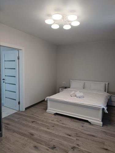 biała sypialnia z łóżkiem i oświetleniem na suficie w obiekcie Квартира на двох, в центрі міста w mieście Mukaczewo
