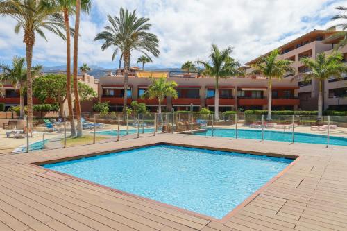 a swimming pool in front of a building with palm trees at Chill in paradise in Playa Paraiso