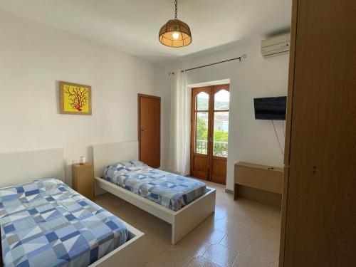a bedroom with two beds and a flat screen tv at Aeolian Apartments in Lipari
