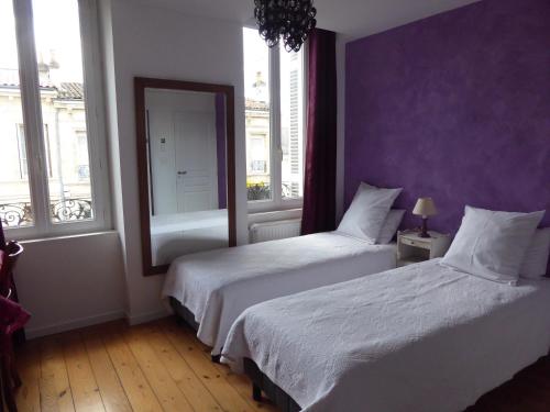 two beds in a bedroom with purple walls and windows at La Maison Bastide in Bordeaux