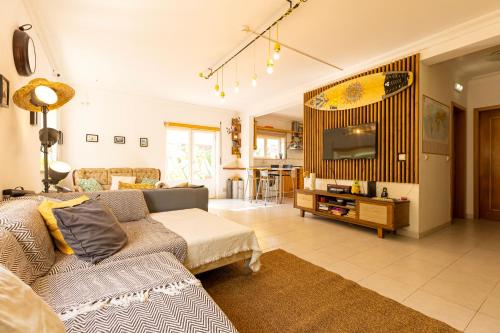 a living room with a couch and a tv at Pineapple Surf House in Peniche
