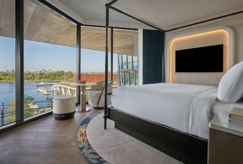 a bedroom with a large bed and a view of the water at Pendry Washington DC - The Wharf in Washington