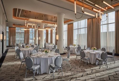 a dining room with tables and chairs and large windows at Pendry Washington DC - The Wharf in Washington