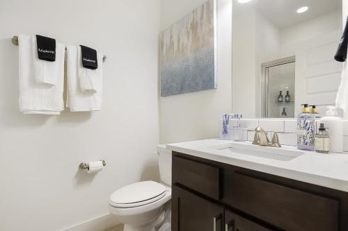 een witte badkamer met een toilet en een wastafel bij The Bourdain in Bentonville