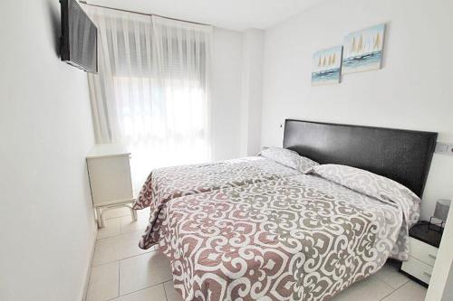 a bedroom with a bed with a comforter and a television at Apartamento 10 Marjal Playa Centro de Guardamar in Guardamar del Segura