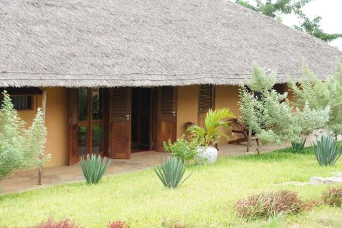 a house with a thatched roof and some plants at Villa Moringa lodge in Lumbo