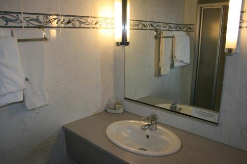 W łazience znajduje się umywalka i lustro. w obiekcie Logis Hotel-Restaurant De La Poste w mieście Urmatt