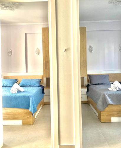a bedroom with two beds and a mirror at Σουίτα Αλέξανδρος in Pefkochori