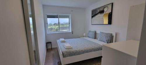 a small white bedroom with a bed and a window at Apartamento Praia-Mar in Ponta Delgada