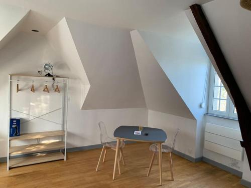 Cette chambre mansardée comprend une table et deux chaises. dans l'établissement Studio un cocon à la campagne, à Saint-Samson-sur-Rance