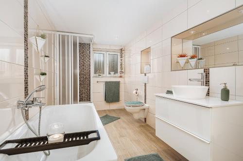 a white bathroom with a tub and a sink at Kleine Koje in Rostock