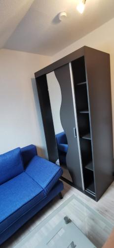 a living room with a blue couch and a cabinet at Ferienwohnung Sternenkieker in Krummhörn