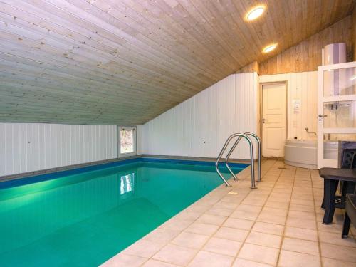 8 person holiday home in Oksb l في Oksbøl: مسبح في بيت بسقف خشبي