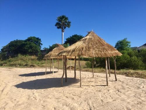 a group of straw umbrellas on a beach at Villa Moringa lodge in Lumbo