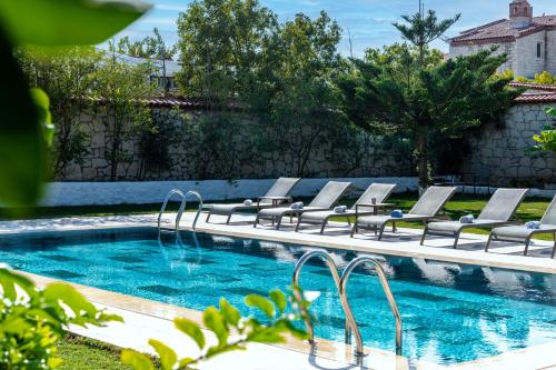 a swimming pool with lounge chairs next to a wall at Alacati Koclu Konagi Hotel in Alacati