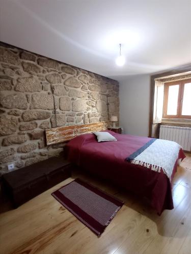 a bedroom with a bed and a stone wall at Casa do Tio Plácido in Valezim