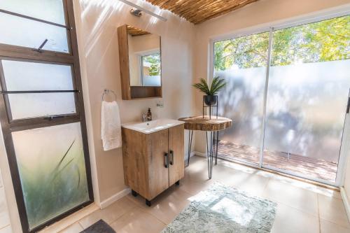 a bathroom with a sink and a mirror and windows at Val de Vine in Stellenbosch