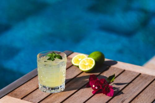 a drink on a wooden table with lime and flowers at Alacati Koclu Konagi Hotel in Alacati
