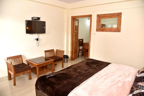 a bedroom with a bed and a table and a tv at Samriti Apartments in Shimla