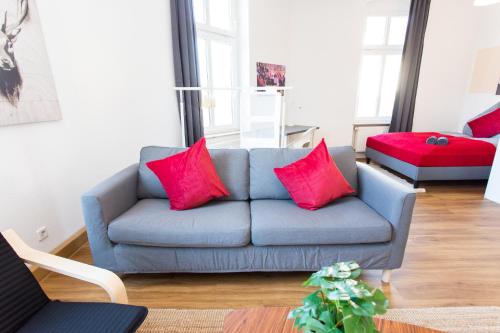 ein Wohnzimmer mit einem blauen Sofa und roten Kissen in der Unterkunft FULL HOUSE Studios - Blue Ocean Apartment - Nespresso in Halle an der Saale