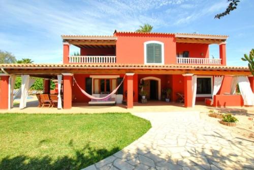 een rood huis met een hangmat ervoor bij Villa Rosada - Private pool & Barbecue in San Jose de sa Talaia