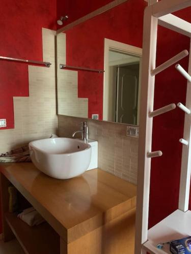 a bathroom with a white sink and a red wall at Casa della Resistenza in Presicce