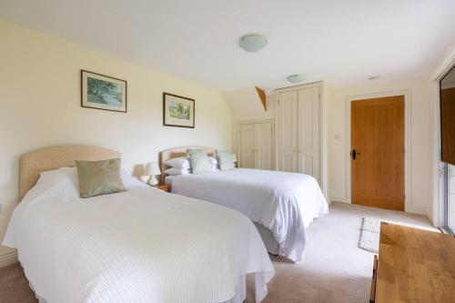 a bedroom with two beds and a chair in it at Dove Lodge in Painswick in Stroud